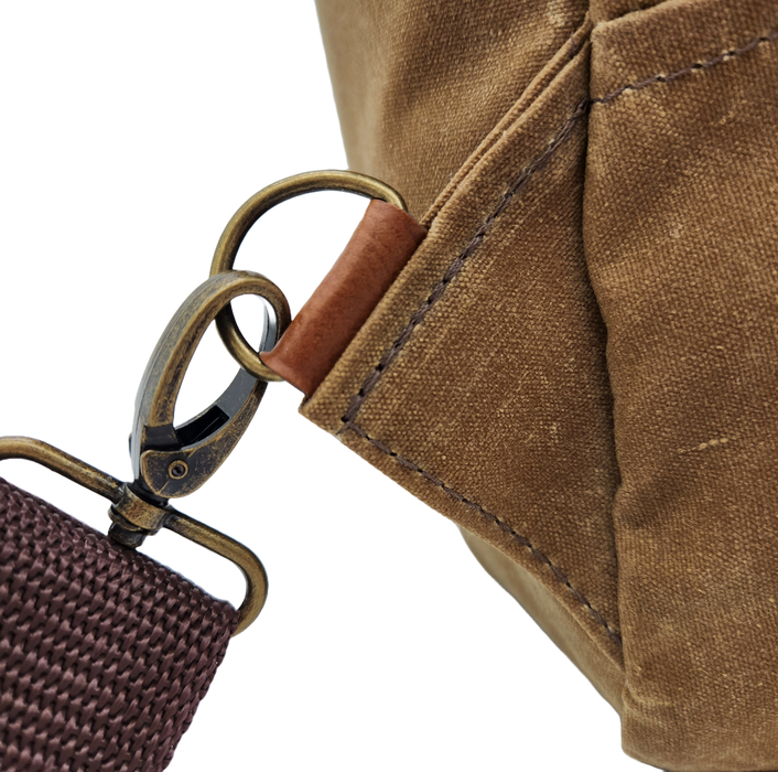 A close up of the strap attachment point to the bag. A rotating clasp and brass d-ring are visible. 